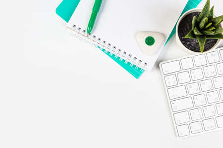 White office desk with blank laptop, computer keyboard and other stationery, potted plant. Top view with copy space, top viewの写真素材