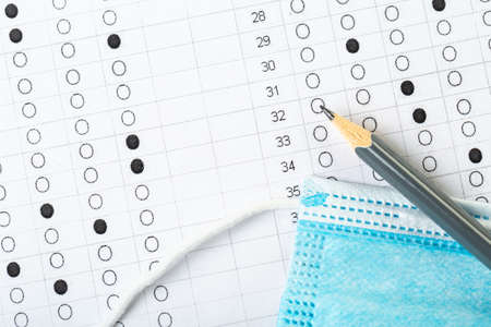 testing in exercise and examination work. computer worksheet with pencil in school test room, lead pencil and medical mask. the concept of education during a pandemicの写真素材