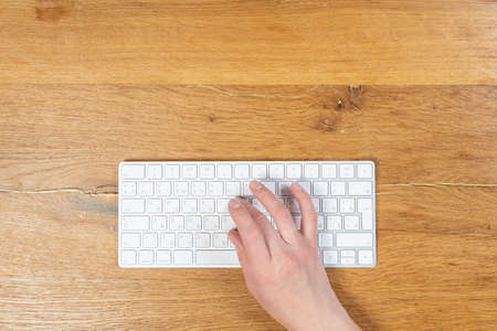 Office worker checks email while sitting at a wooden table.