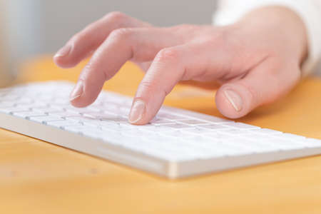 Woman office worker typing on white keyboardの写真素材