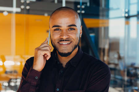 Happy african american businessman businesswoman with mobile phone in hands in modern office....