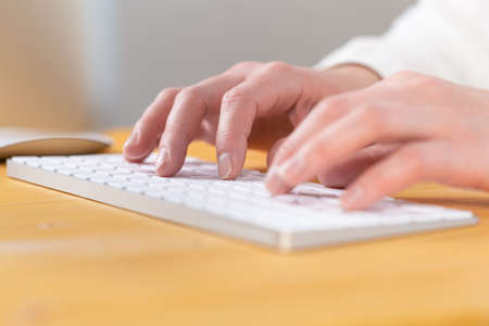 Office worker checks email while sitting at a wooden table.の写真素材