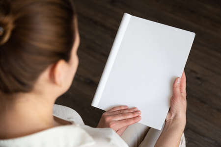 beautiful female hands holding white magazine with blank cover mock up at home