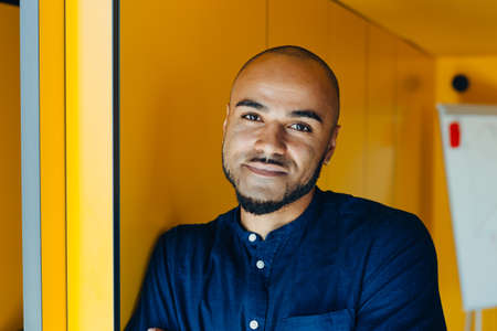 Handsome cheerful african american executive business man in office workspace. Concept of young people work in free scheduleの写真素材