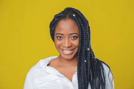 beautiful african american girl in a white shirt rejoices and smiles on a yellow backgroundの写真素材
