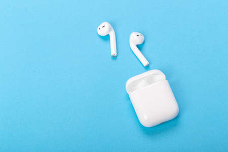 Modern wireless headphones with charging case on a blue background. The concept of modern...