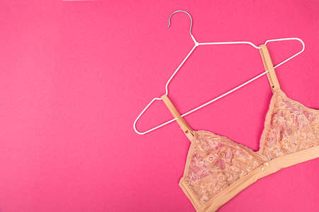 Top view of stylish women bra on white hanger on pink background with copy space. Women's wardrobe, shopping concept.の写真素材