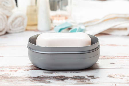 soap on gray plastic soap dish with towels on white wooden table in bathroomの写真素材