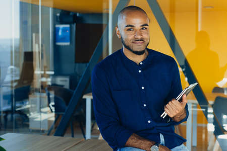 Happy african american businessman or or creative man with tablet in hands in modern free office, coworkingの写真素材