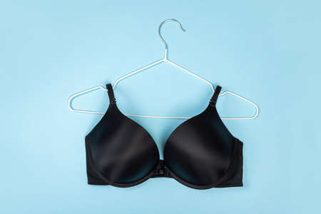 Top view of stylish women bra on white hanger on light blue background with copy space. Women's wardrobe, shopping concept.の写真素材