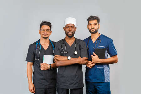 attractive medical team standing together over light gray background. African American nurse and two...