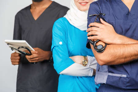 Group of paramedics smiling over gray background. muslim doctor woman with colleagues african and indian surgeonの写真素材