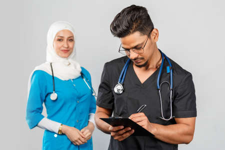 beautiful muslim doctor woman and indian nurse in glasses discuss tasks. portrait of beautiful...