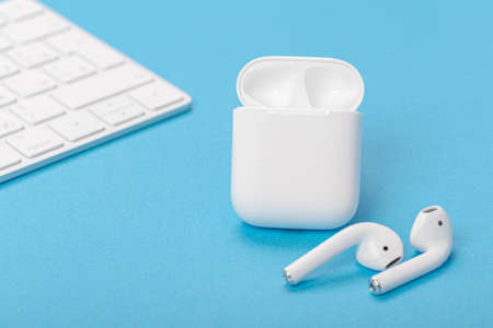 Modern wireless headphones with charging case on a blue background. The concept of modern...