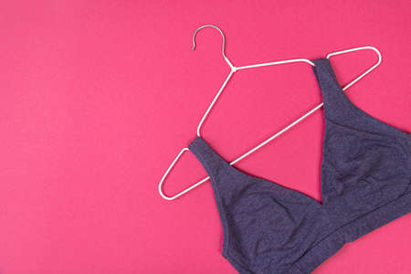 Top view of stylish women bra on white hanger on pink background with copy space. Women's wardrobe, shopping concept.の写真素材