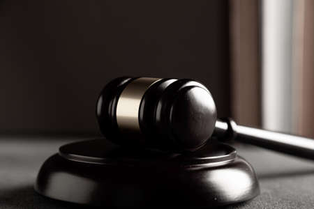 Judge's gavel on a dark background in the library with different books. Law concept