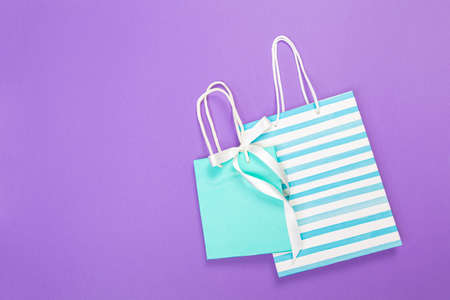 colored eco Paper shopping bag on purple background. close up mock up template for design and text.の写真素材