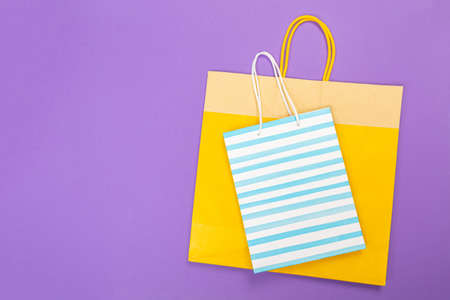 colored eco Paper shopping bag on purple background. close up mock up template for design and text.の写真素材