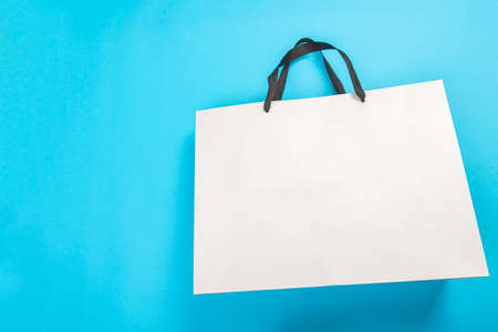 eco blank white paper carry bag with shopping handles facing forward on blue backgroundの写真素材