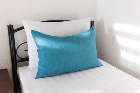 Two beds in a hotel room. white and blue pillows on a white sheet sunbeamsの写真素材