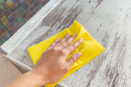 Cleaning yellow napkin in the hands of a woman. cleaning service. The concept of disinfection....