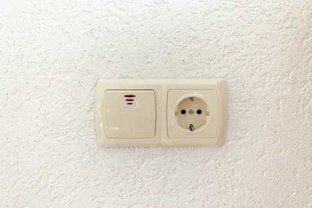 white socket and light switch on empty wall