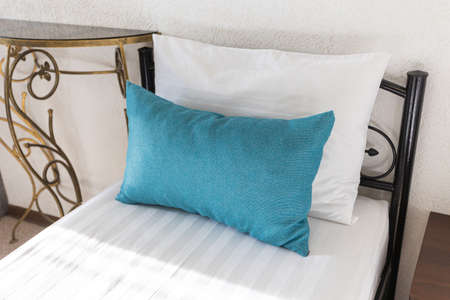 Two beds in a hotel room. white and blue pillows on a white sheet sunbeamsの写真素材