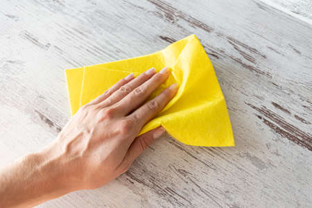 Cleaning yellow napkin in the hands of a woman. cleaning service. The concept of disinfection. Protection against viruses and bacteriaの写真素材