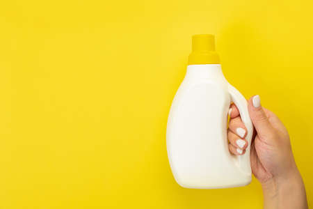 Cleaner's hand holding a chemical spray bottle. Empty space for text or logo on a yellow background. Early spring or regular cleaning. Cleaning and cleaning concept.の写真素材