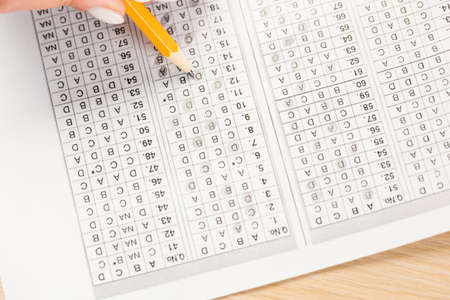 Students hands to take exams, writing an exam room with a pencil holding on an optical form of a...