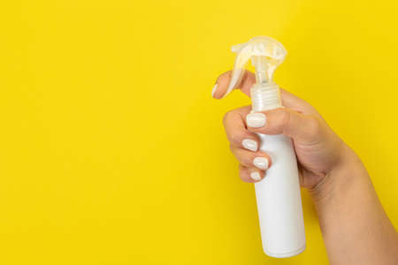 Cleaner's hand holding a chemical spray bottle. Empty space for text or logo on a yellow background. Early spring or regular cleaning. Cleaning and cleaning concept. flat layの写真素材