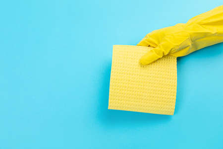 female hand in yellow rubber protective glove with micro fiber yellow rag for. washing dishes. A...
