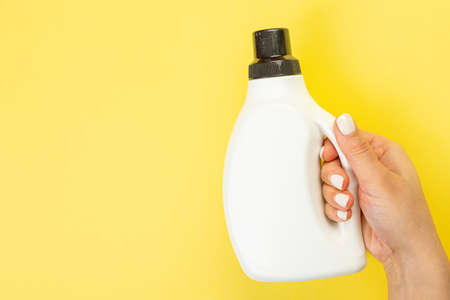 Cleaner's hand holding a chemical spray bottle. Empty space for text or logo on a yellow background. Early spring or regular cleaning. Cleaning and cleaning concept.の写真素材