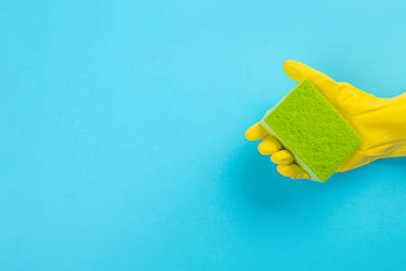 worker's hand in yellow rubber protective glove with micro fiber green sponge or washcloth. A maid or housewife takes care of the house. general or regular cleaning.の写真素材