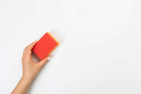 Housewife's hand holds a sponge for cleaning agent on a gray background. Detergent for various surfaces in the kitchen, bathroom and other rooms.の写真素材