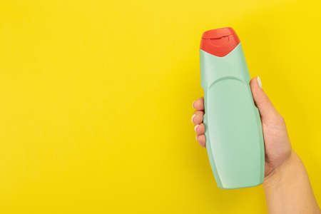 Cleaner's hand holding a chemical spray bottle. Empty space for text or logo on a yellow background. Early spring or regular cleaning. Cleaning and cleaning concept.の写真素材