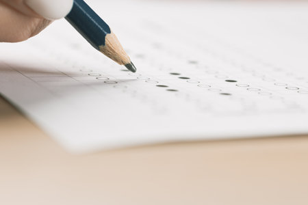 Students hands to take exams, writing an exam room with a pencil holding on an optical form of a...