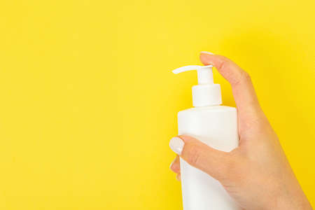 Cleaner's hand holding a chemical spray bottle. Empty space for text or logo on a yellow background. Early spring or regular cleaning. Cleaning and cleaning concept.の写真素材
