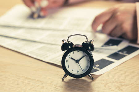 alarm clock with time running out. Students hands to take exams, write examination room with pencil holding on optical form of standardized test with answersの写真素材