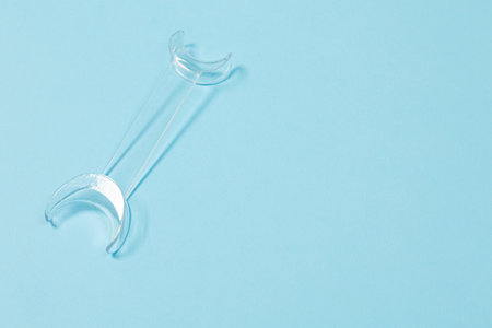 Retractor Dental lip retractor Access to the oral cavity. Wide mouth opening for a dental procedure on blueの写真素材