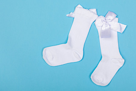 high white children's socks with big bows for festive clothes on a blue backgroundの写真素材