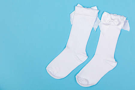 high white children's socks with big bows for festive clothes on a blue backgroundの写真素材
