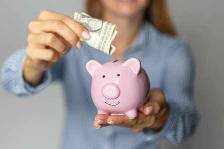 female hands put euro money in a pink piggy bank. The concept of saving money or savings, investmentの写真素材