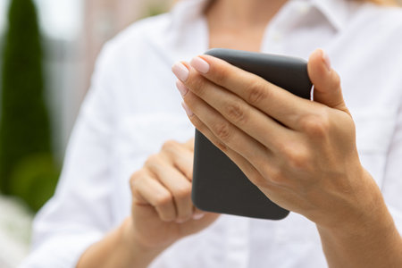 female hands hold a modern mobile phone on the street. news, education, modern app, shopping order, work onlineの写真素材