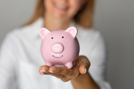 female hands holding pink piggy bank indoors investment accumulation crisisの写真素材