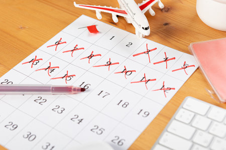 Calendar and reminders for business trip, travel and vacation. planner with airplane model on desktop with keyboard, mouse, coffee and succulent. marking important dates and days in a diary at the office desk. Reminder conceptの写真素材
