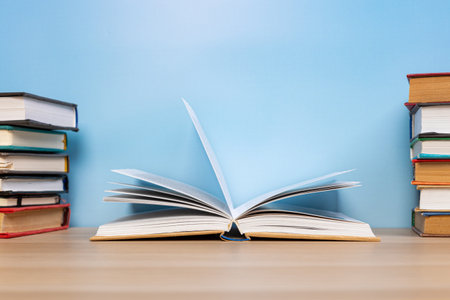 Stack of books in the colored cover lay and open book whith old pages on the wooden table and blue backround. education learning conceptの写真素材