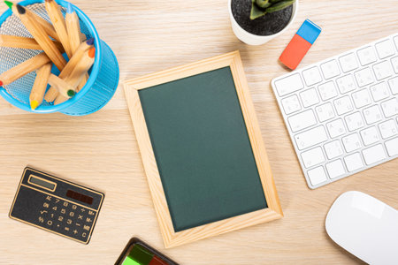 School chalkboard mockup on work desk. Composition of a student's desk with stationery items, toys, snack. Empty board for promo textの写真素材