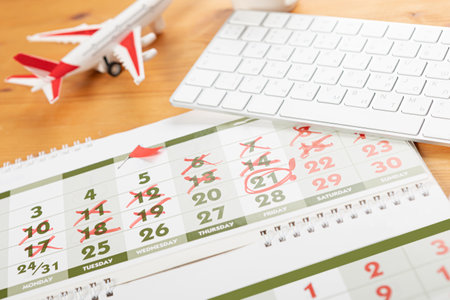 Calendar and reminders for business trip, travel and vacation. planner with airplane model on desktop with keyboard, mouse, coffee and succulent. marking important dates and days in a diary at the office desk. Reminder conceptの写真素材