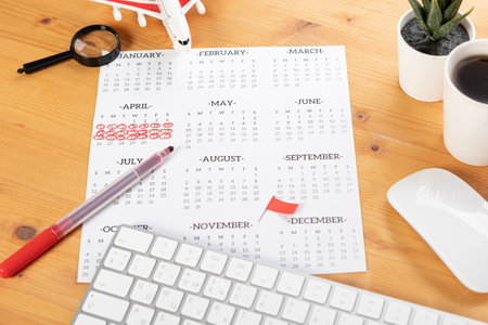Calendar and reminders for work trips, travel and vacations. glider on desktop with airplane and magnifying glass and pen, keyboard. marking important dates and days in a diary at the office desk. 2023 calendar reminder concept.の写真素材